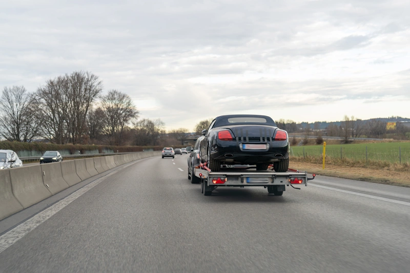 Transporting a passenger car on a car trailer using car transport straps