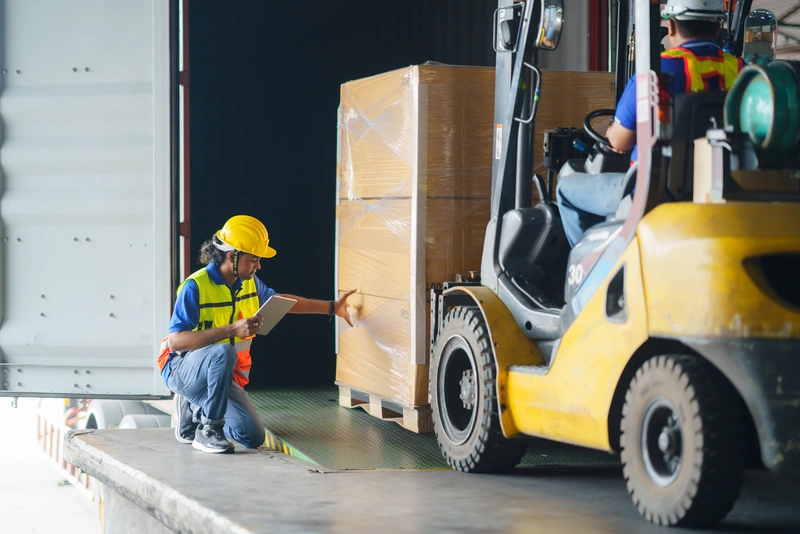 A pallet is loaded into a truck with a forklift